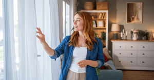 Woman opening curtains at home