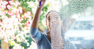 Young woman washing window
