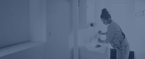 A pregnant woman uses a plunger to unclog a bathroom sink