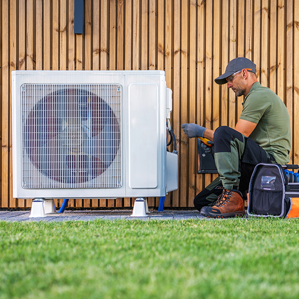 An HVAC repairman tunes up an outdoor air conditioning condenser. An HVAC repairman tunes up an outdoor air conditioning condenser.